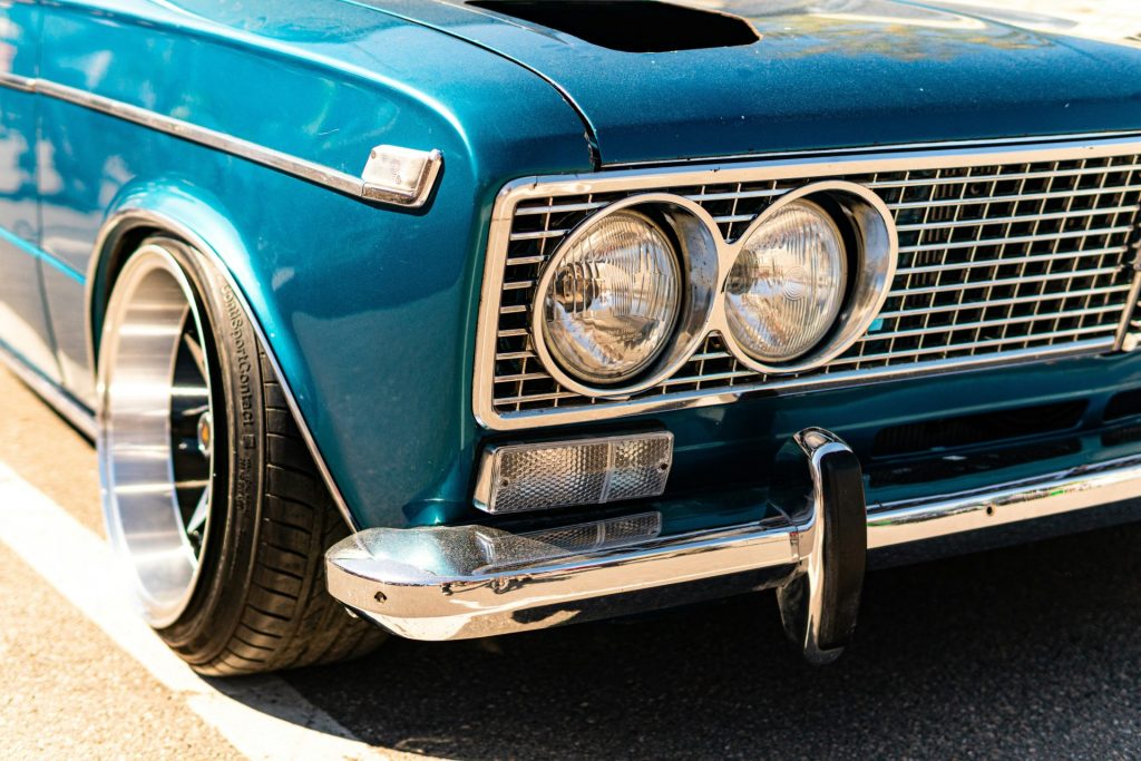 Teal classic car with chrome bumper, grille, and headlights