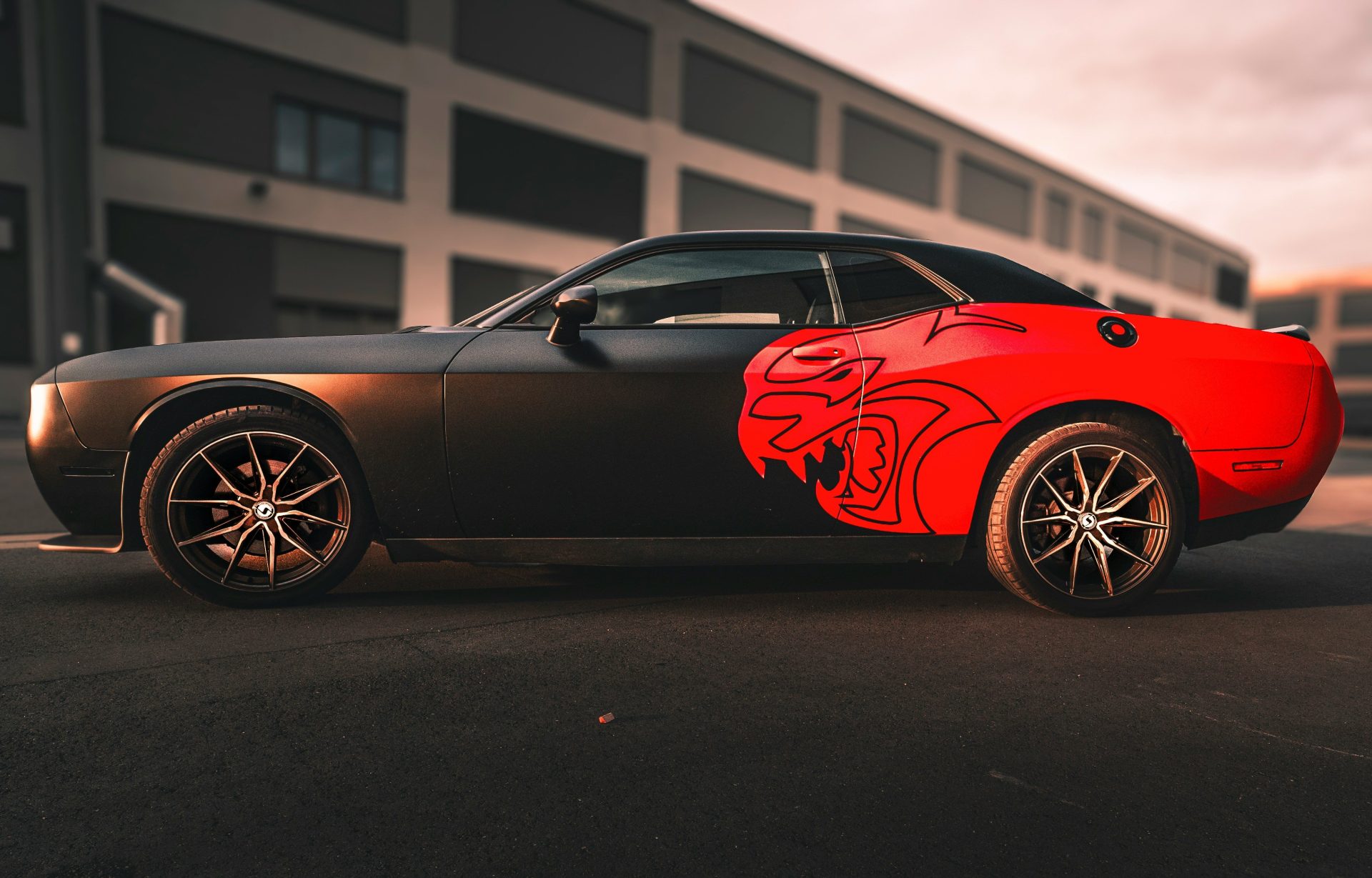 A red and black sports car parked in front of a building